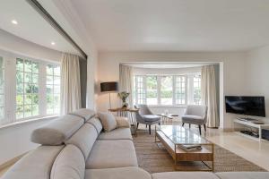 un soggiorno con un grande divano e una TV di Unique beach Villa with ocean view pool tennis a Cascais