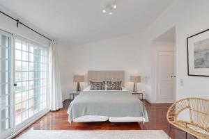 a white bedroom with a large bed and large windows at Unique beach Villa with ocean view pool tennis in Cascais