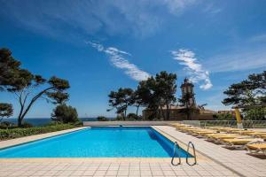 a swimming pool with lounge chairs and a lighthouse at Unique beach Villa with ocean view pool tennis in Cascais