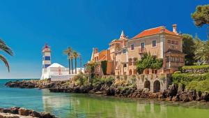 un faro e un edificio vicino all'acqua di Unique beach Villa with ocean view pool tennis a Cascais