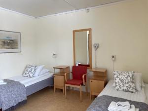 a room with two beds and a chair and a mirror at STF Malmfältens Folkhögskola in Kiruna