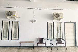 three chairs and a table in front of a wall with mirrors at Pondokan Guest House Rinjani Syariah in Bengkulu