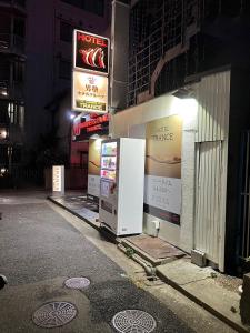 zwei Kühlschränke an der Seite eines Gebäudes in der Nacht in der Unterkunft ホテル トランス 男塾ホテルグループ in Kōbe