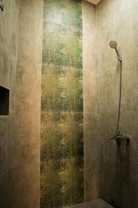 a shower stall with a green and gold wallpaper at Nima guest house in Nizwa