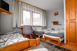 a bedroom with two beds and a chair and a window at U Cudzicha in Zakopane