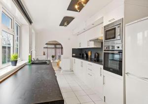 uma cozinha com armários brancos e um balcão preto em 3 Bedroom House, great location - Big special offer for long-term stays em North Hykeham