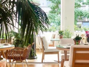 un comedor con mesas, sillas y plantas en Grecotel Pallas Athena, en Atenas