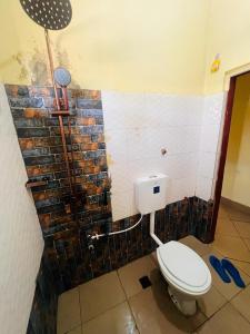 a bathroom with a toilet and a brick wall at Ukali ukalini homes in Sanya Juu