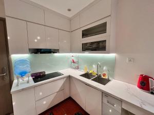 uma cozinha branca com armários brancos e um lavatório em Skyhome em Gia Lâm Pho