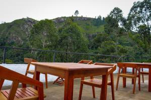 uma mesa e cadeiras num pátio com uma montanha em Rock n Fall Nature Resort em Ella