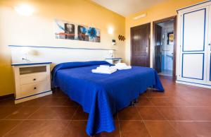 a bedroom with a blue bed with towels on it at Residence Hotel La Pelosetta in Stintino