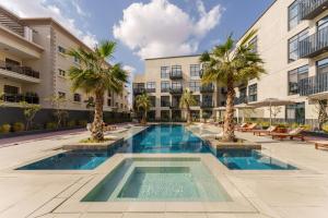 einem Pool mit Palmen vor einem Gebäude in der Unterkunft Cozy Studio in Beverly Residence, JVC by Suiteable in Dubai