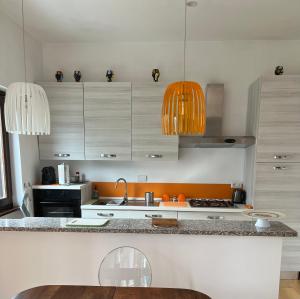 a kitchen with white cabinets and orange pendant lights at Filippo's House in Palidoro