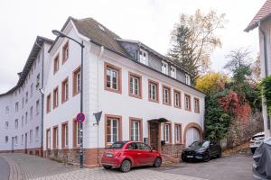 a red car parked in front of a white building at LIT LIVING Weinheim Altstadt - Boutique Apartments - Parking in Weinheim