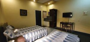 a bedroom with two beds and a desk and a television at Felicidad Resto and Pension House in General Santos