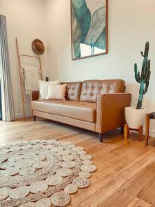 un sofá de cuero en una sala de estar con cactus en 'NEL' - Rye Beach Studio Retreat, en Rye