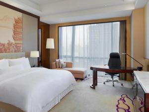 a bedroom with a large bed and a desk and a desk at The Westin Wuhan Wuchang in Wuhan