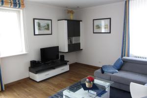 ein Wohnzimmer mit einem Sofa und einem TV in der Unterkunft Dünenpark Binz - Düne 11 Apartment 89 in Binz