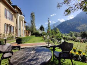 a patio table with chairs and a view of a mountain at Forest Hill Resorts Laripora in Pahalgām