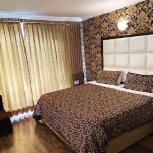 a bedroom with a large bed with a large window at Forest Hill Resorts Laripora in Pahalgām