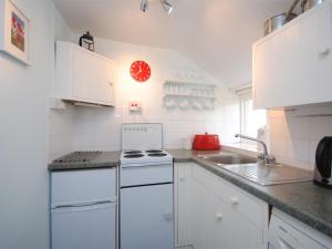 a white kitchen with a stove and a sink at 1 Bed in Burton Bradstock DC016 in Burton Bradstock