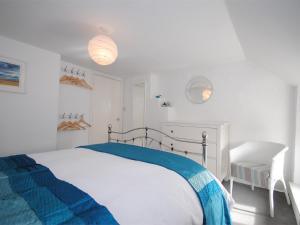 a white bedroom with a bed with a blue blanket at 1 Bed in Burton Bradstock DC016 in Burton Bradstock