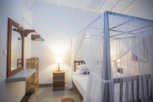 ウナワトゥナにあるTHE CHILLI STUDIO APARTMENTのベッドルーム(天蓋付きベッド1台、鏡付)
