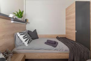 uma pequena cama num quarto com uma parede de madeira em Apartma LeMa em Velike Lašče