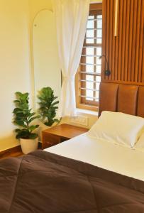 een slaapkamer met een bed en een raam met een plant bij SHORE STORIES in Alleppey