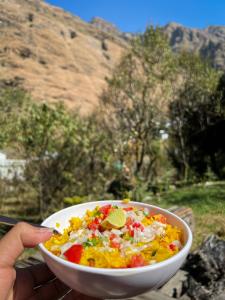 a person is holding a bowl of food at Boho Grove Cafe & Stay, Tirthan Valley in Banjār