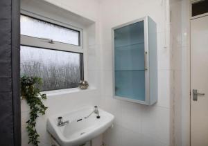 a white bathroom with a sink and a window at Charming Family Apartment - Stay Longer, Save More! in Lincolnshire