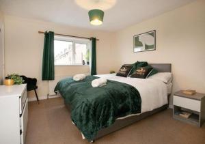 a bedroom with a large bed with a green blanket at Charming Family Apartment - Stay Longer, Save More! in Lincolnshire