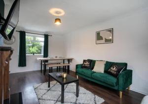 - un salon avec un canapé vert et une table dans l'établissement 3 Bedroom Apartment with non-smoking room - Family & business trip, à Lincolnshire
