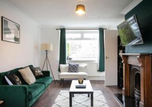 a living room with a green couch and a fireplace at Charming Family Apartment - Stay Longer, Save More! in Lincolnshire