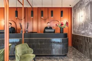 a lobby with orange walls and a man sitting at a desk at Residenza Piranesi by Tree Charme in Rome