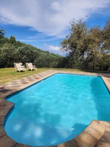 a blue swimming pool with two chairs in a yard at Viewpoint - Cabin 2 in Haenertsburg