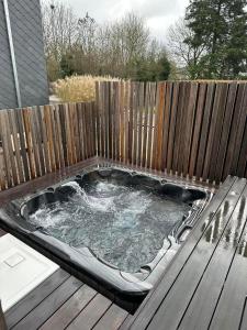 un bain à remous sur une terrasse avec une clôture en bois dans l'établissement Villa Le Brame, à Ciney
