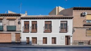 a white building with windows and balconies on a street at Apartamentos Granadal in Toledo