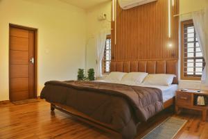 a bedroom with a large bed with a wooden headboard at SHORE STORIES in Alleppey