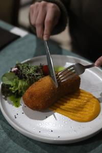 a person holding a fork and knife over a plate of food at Vershyna in Dragobrat