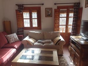 Una sala de estar con un sofá y un televisor. en La casita del castaño en Bubión, en Bubión
