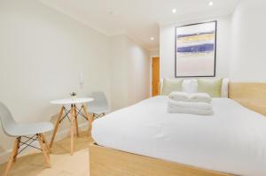 een slaapkamer met een wit bed en 2 stoelen bij Queensborough Terrace Serviced Apartments by Concept Apartments in Londen