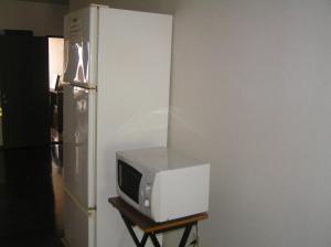 eine Mikrowelle auf einem Stand neben einem Kühlschrank in der Unterkunft Pension Young House in Furano
