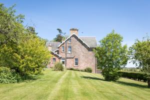 an old brick house with a large grass yard at Whitehouse Country House in Saint Boswells