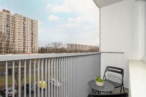 d'un balcon avec une table, une chaise et une fenêtre. dans l'établissement Stylish Two Bedroom Apartment with Parking Near Lake Malta in Poznań by Noclegi Renters, à Poznań