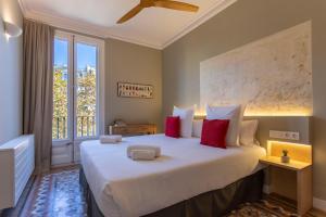 a bedroom with a large white bed with red pillows at Bcn Paseo De Gracia Rocamora Apartment in Barcelona