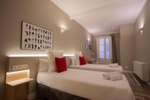 two beds with red pillows in a room at Bcn Paseo De Gracia Rocamora Apartment in Barcelona