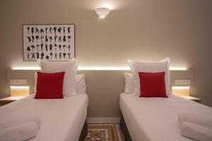 two beds with red pillows in a room at Bcn Paseo De Gracia Rocamora Apartment in Barcelona
