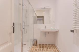 a white bathroom with a sink and a shower at Bcn Paseo De Gracia Rocamora Apartment in Barcelona