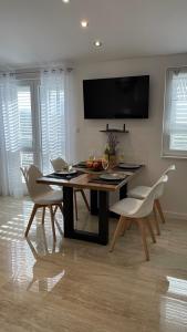 une salle à manger avec une table et des chaises blanches dans l'établissement Apartment Julia, à Podgreben